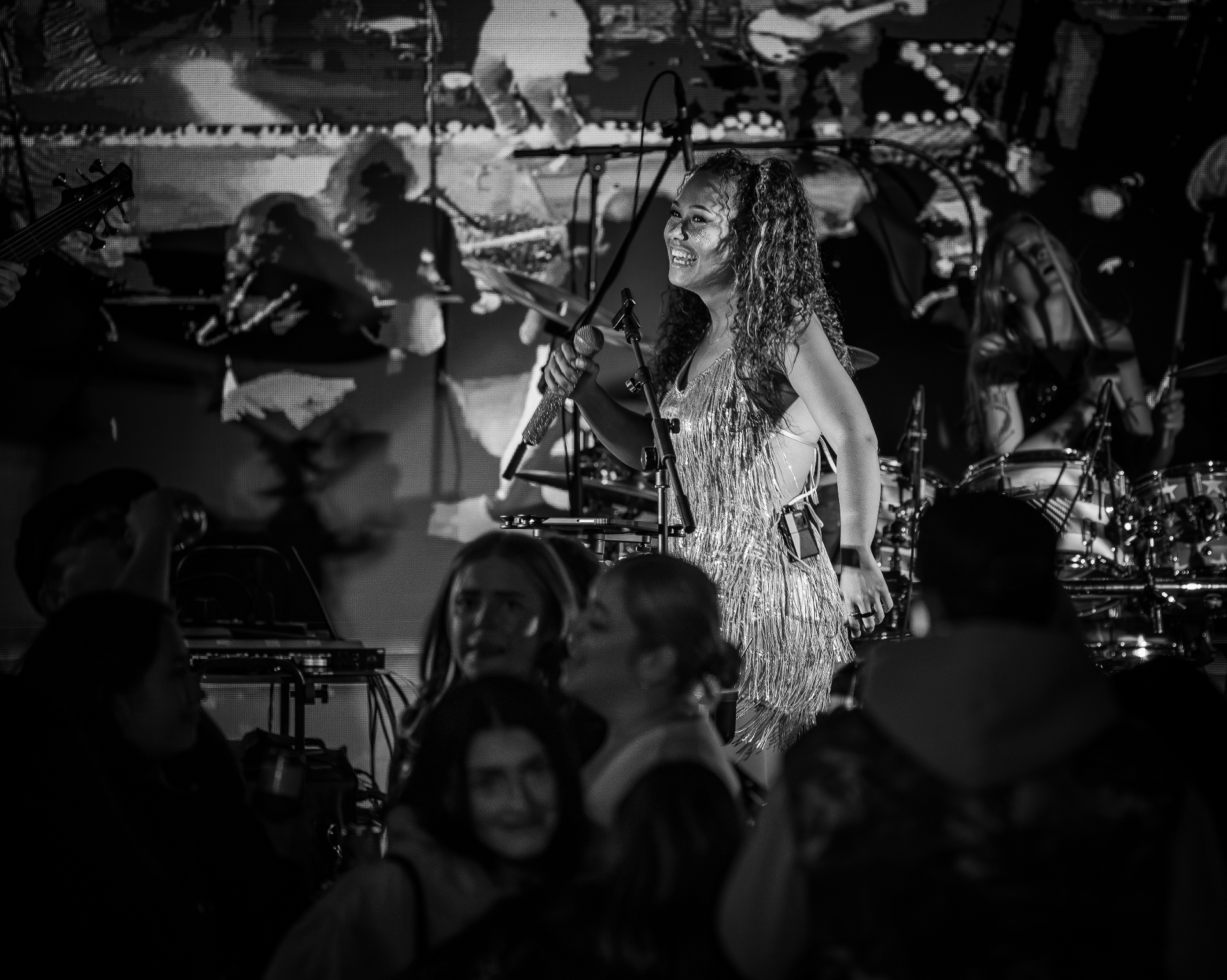 Manix Rho lead singer smiling on stage with crowd in foreground