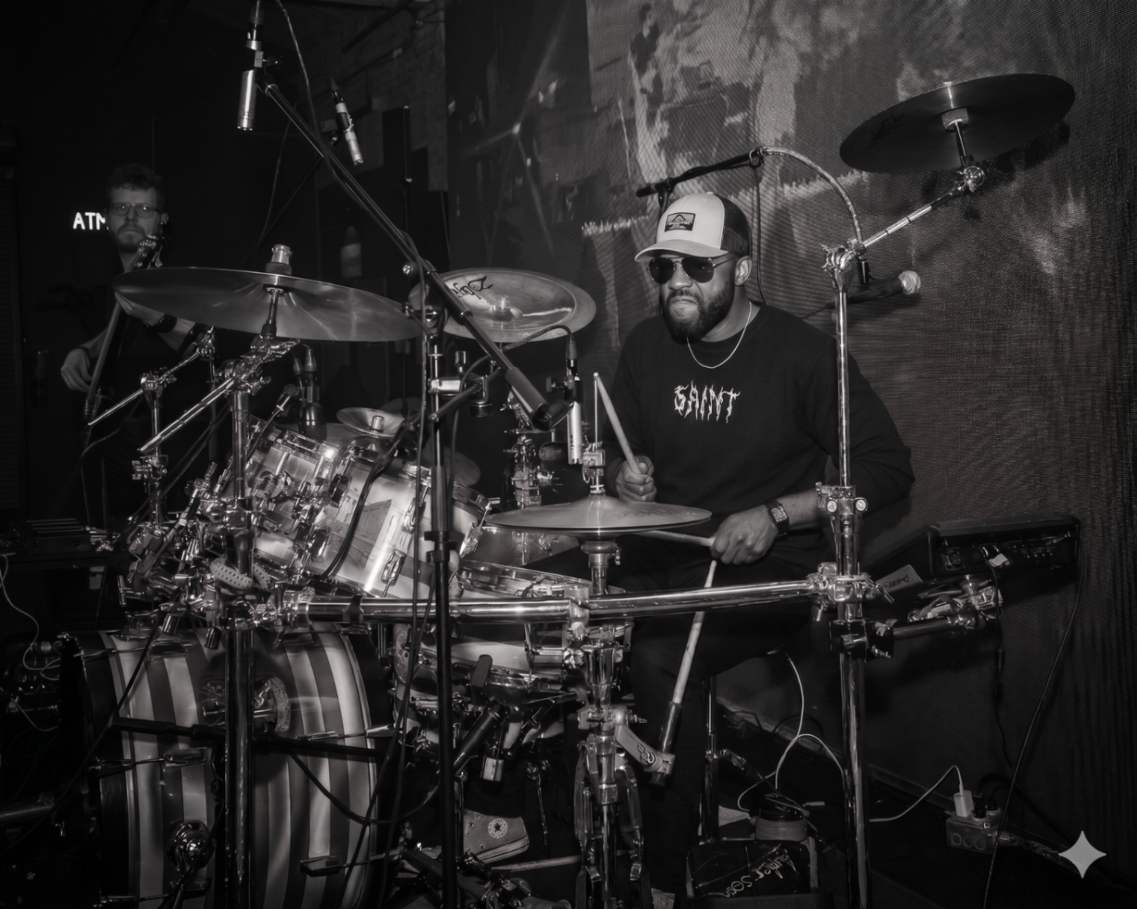 Manix Rho drummer in cap and sunglasses performing live behind kit